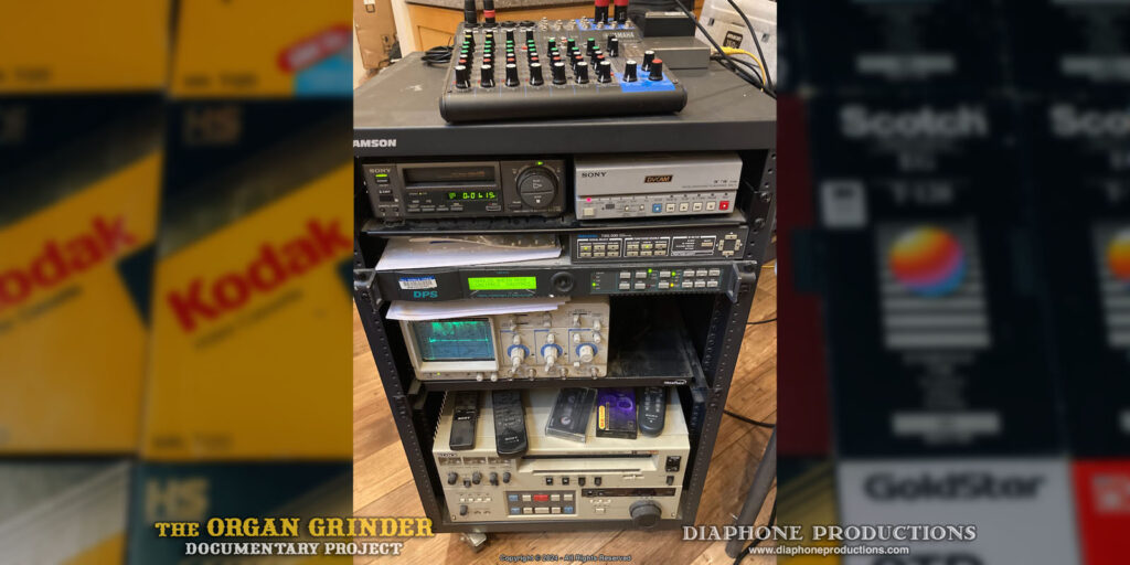 A table-height A/V rack cart containing various vintage tape players, test equipment, and a small waveform monitor. An audio mixer sits on top.