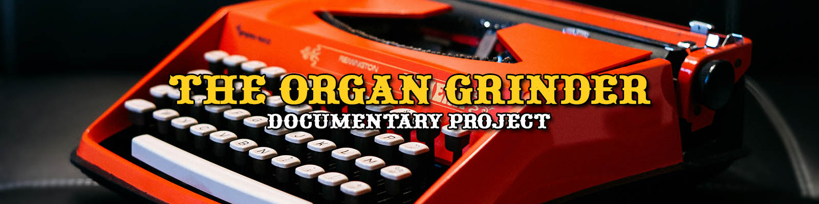 An orange vintage manual typewriter with white keys sits on a black leather sofa cushion.