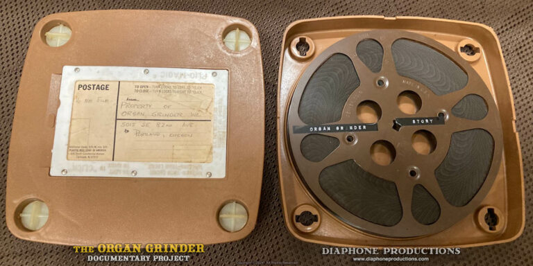 A vintage 16mm film reel, displayed in its shipping container. An old-style Dymo label on the film reel reads "The Organ Grinder Story".